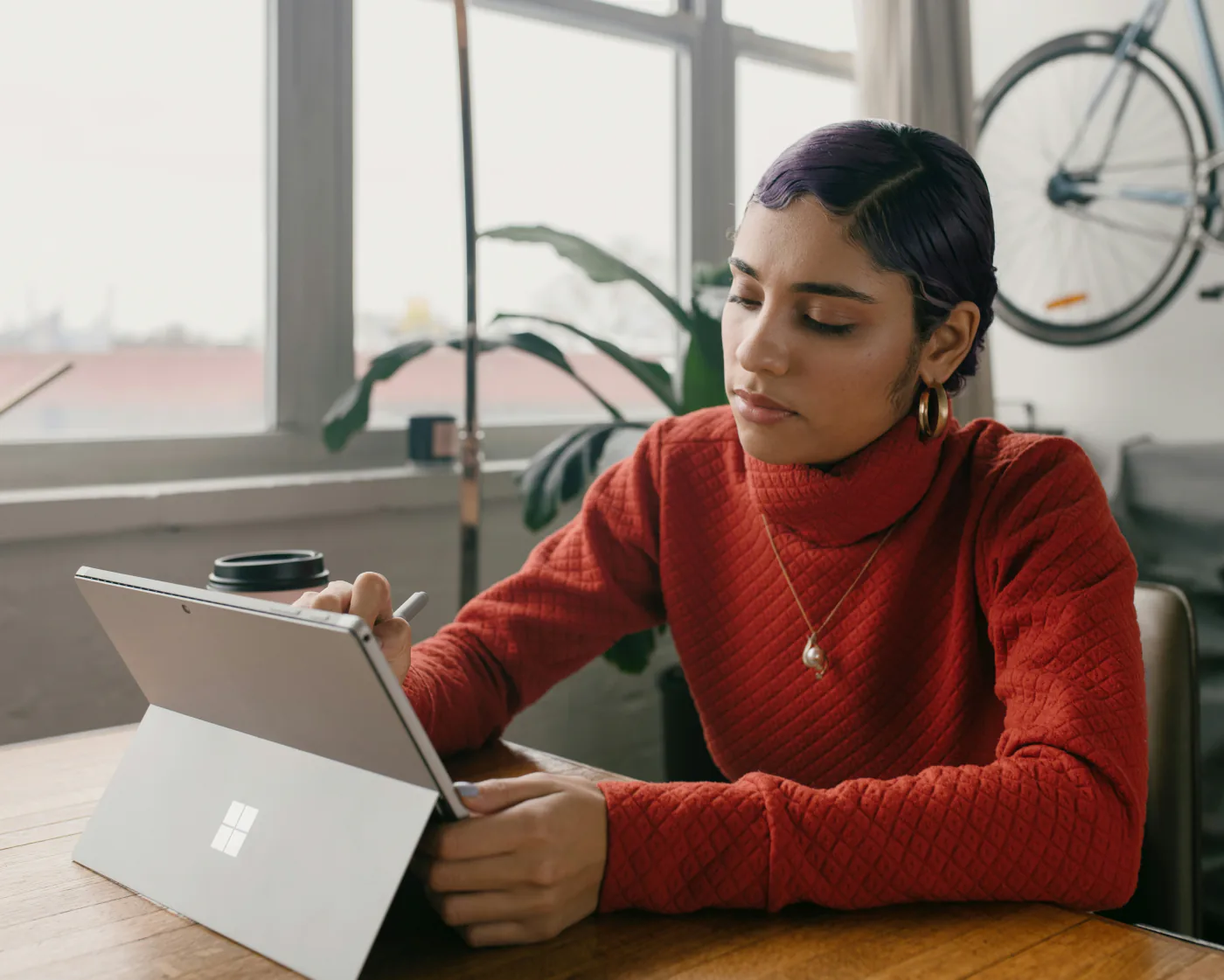 Une consultante en pull terracotta prend des notes sur sa tablette dans un bureau lumineux